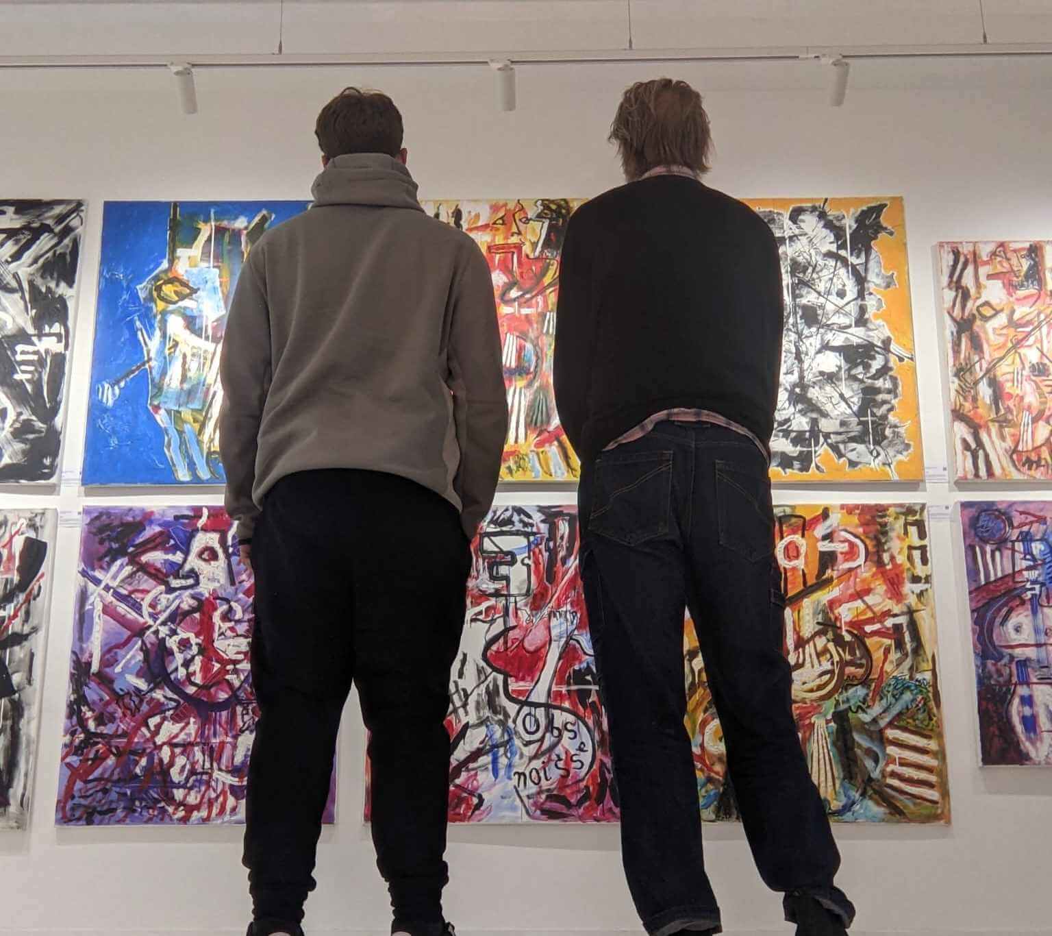 Two young people looking at abstract paintings in an art gallery