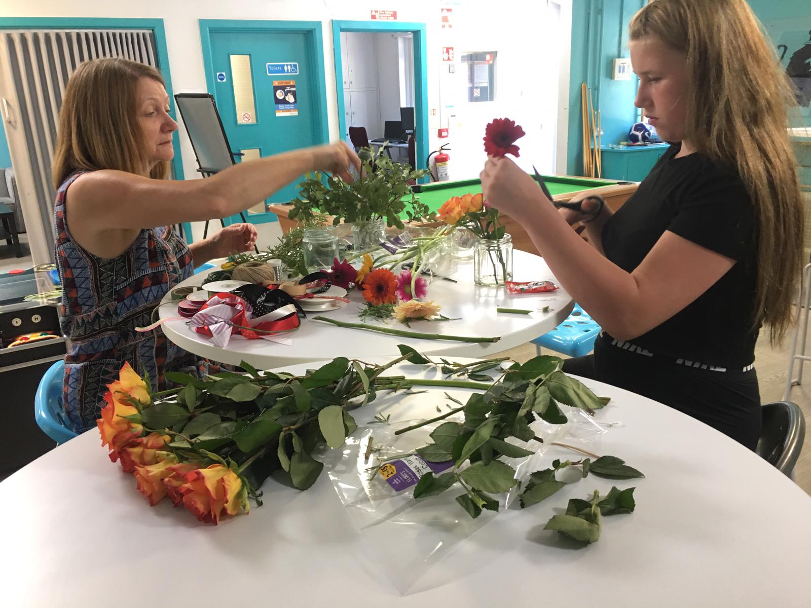 A young person and mentor taking part in a flower arranging activity together