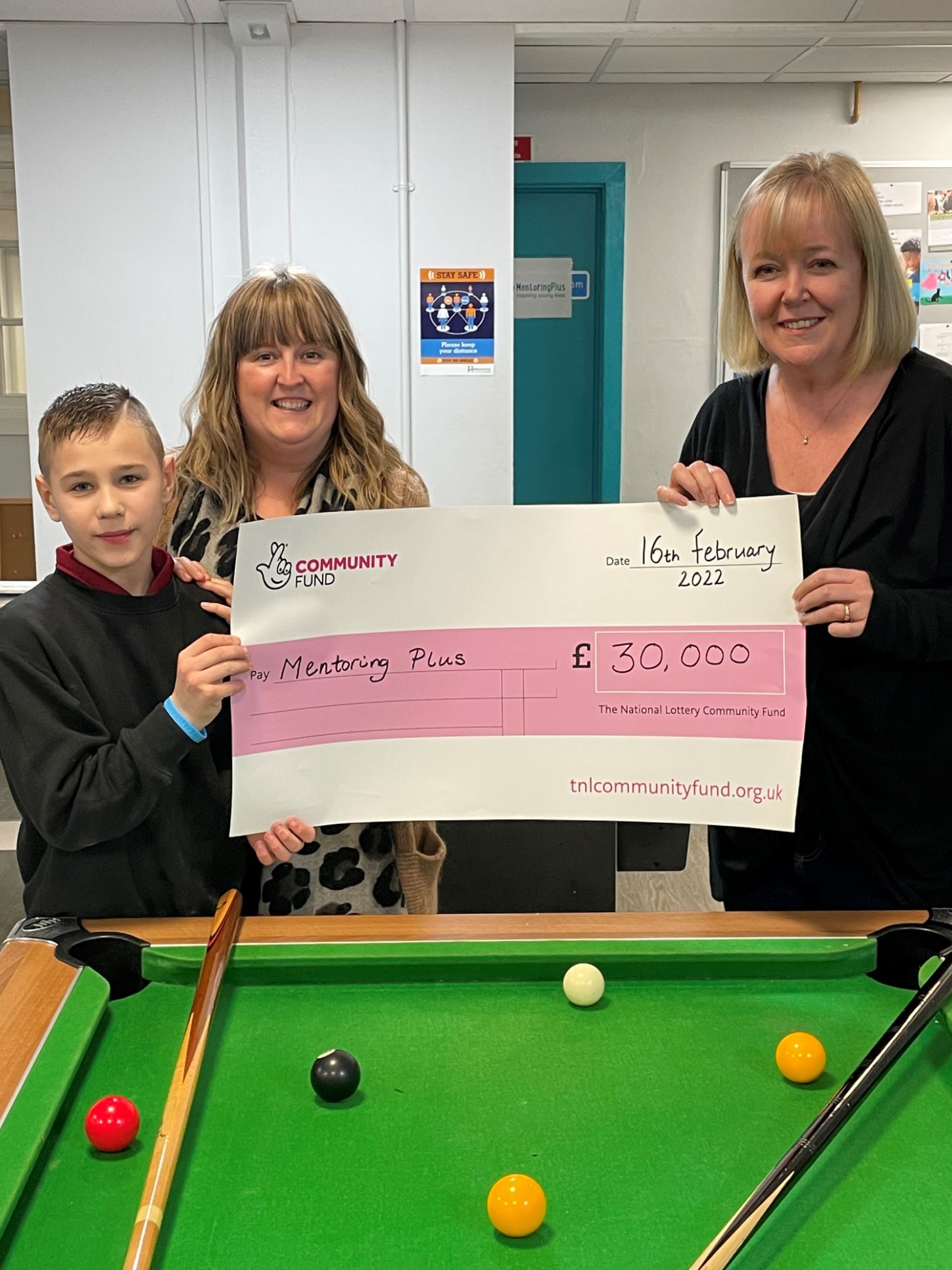 Mentoring Plus staff and a young person holding a £30,000 cheque from the National Lottery Community Fund