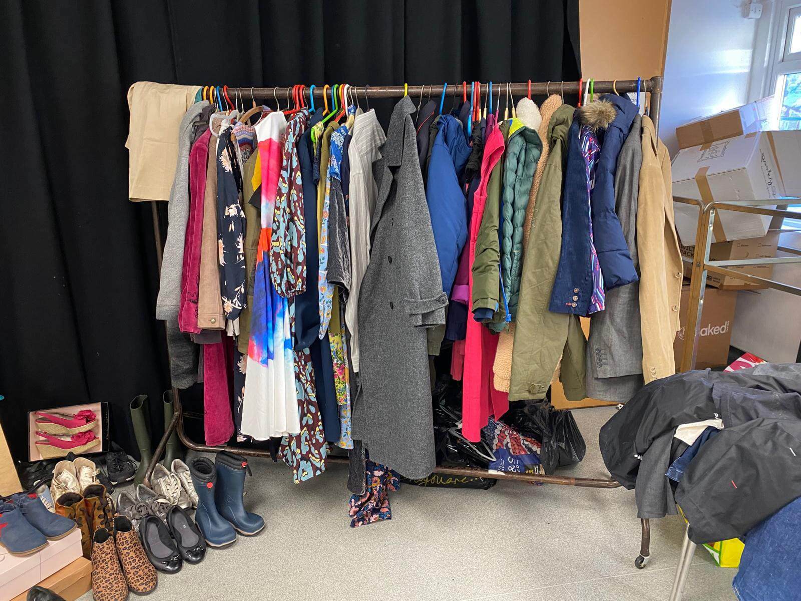 A rail of donated preloved clothes and shoes at a Mentoring Plus fundraising sale