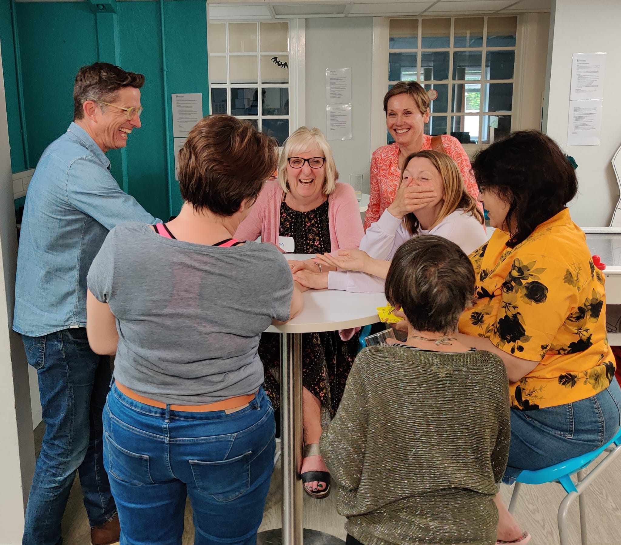 Volunteers laughing together around a table during a Mentoring Plus training session