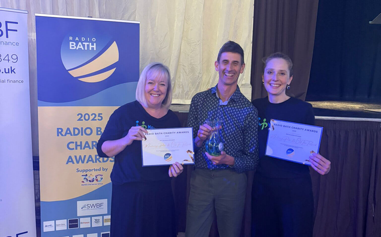 Mentoring Plus representatives holding certificates and a trophy at the Radio Bath Charity Awards 2025