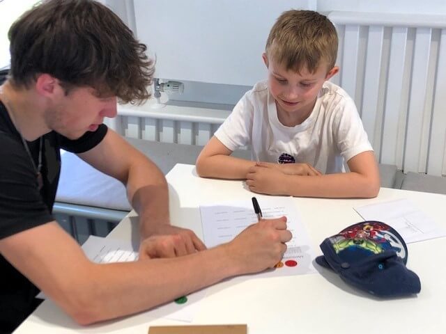 A Kingswood School student mentoring a younger pupil at a table
