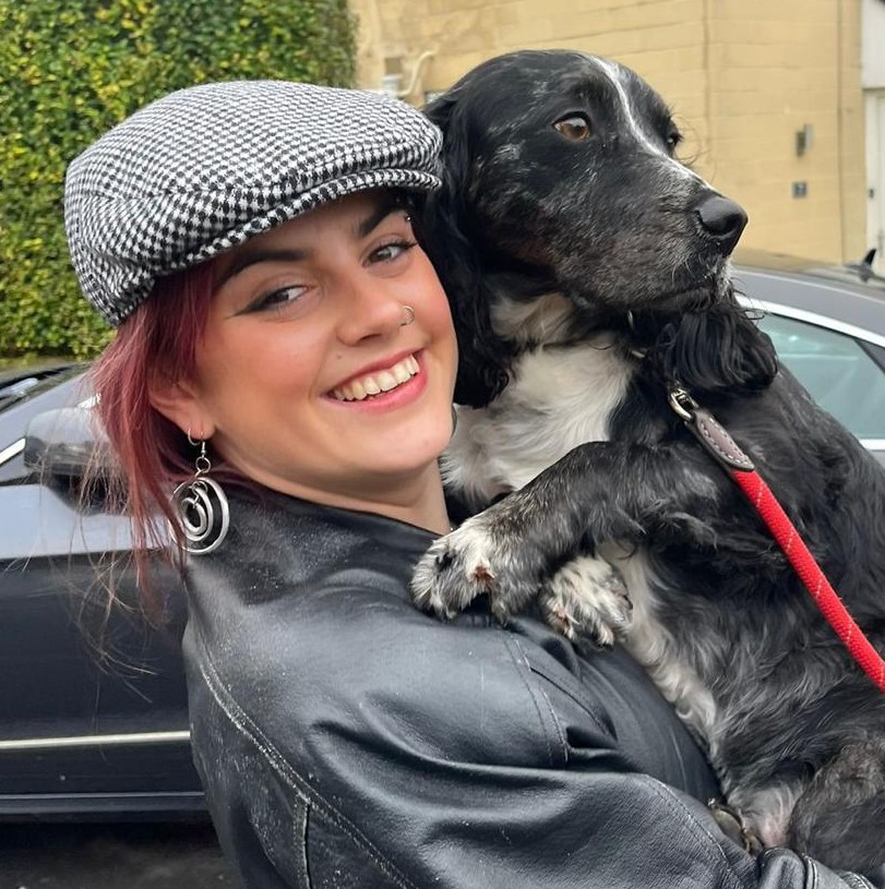 Photo of Evie holding a dog and smiling at the camera